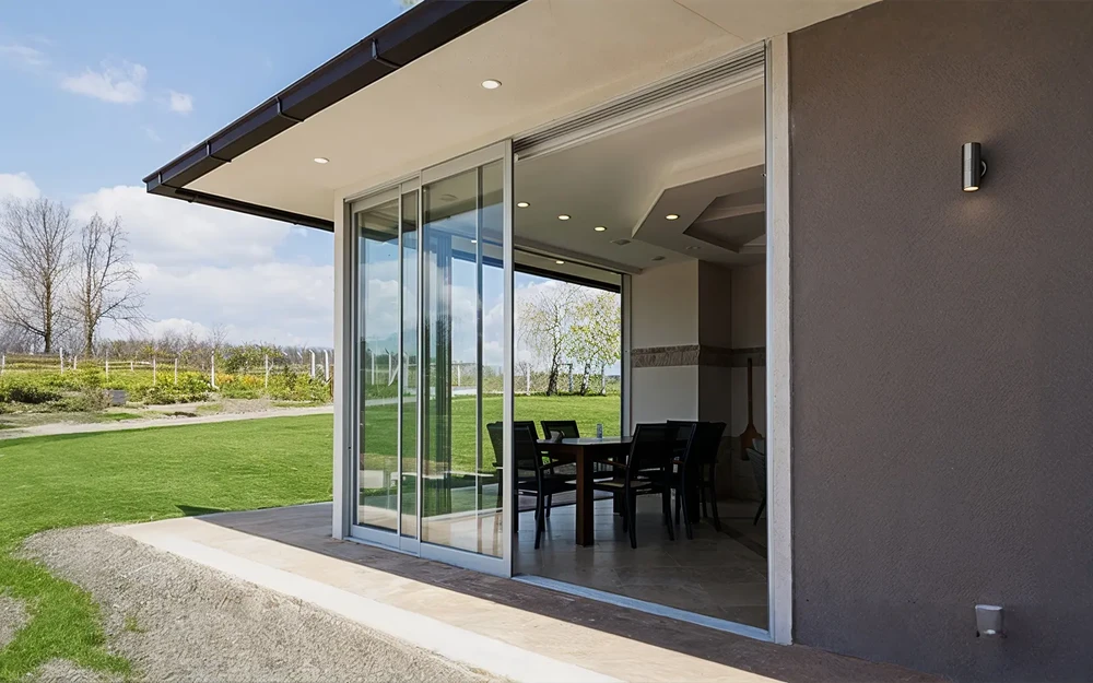 Maison moderne avec grande baie vitrée coulissante ouverte sur jardin verdoyant