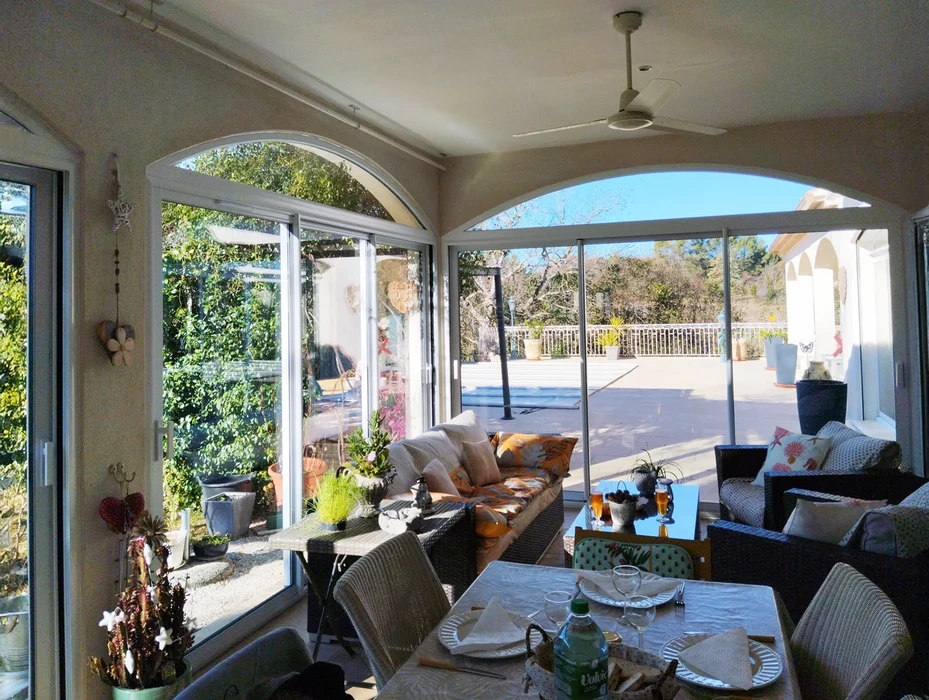 Véranda moderne avec salon confortable donnant sur terrasse extérieure