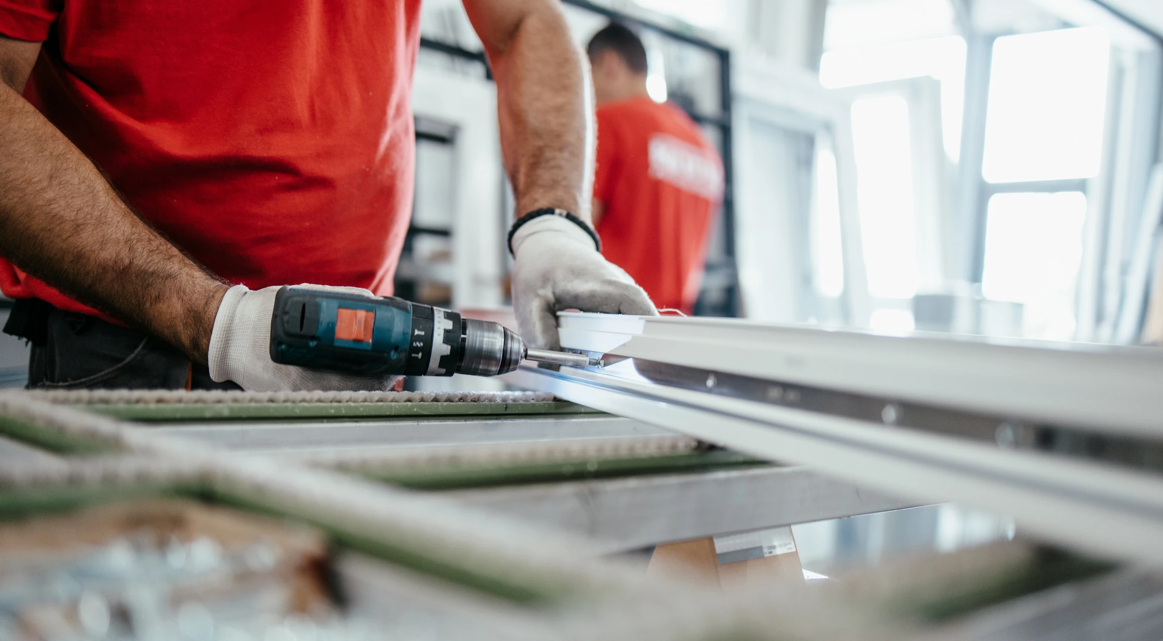 Le travailleur manuel travaille dans une usine de menuiserie, il monte des fen&ecirc;tres et des portes en PVC