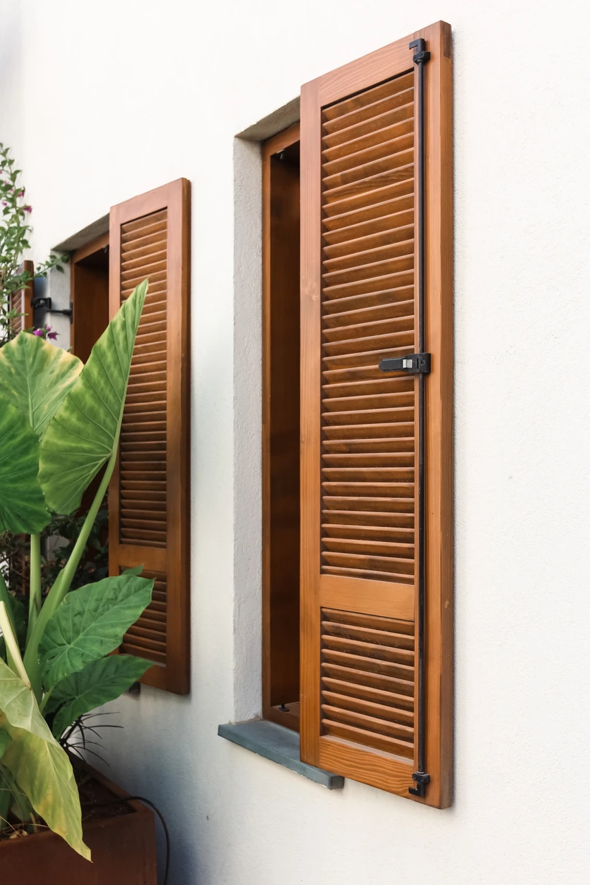 Fa&ccedil;ade ext&eacute;rieure de b&acirc;timent r&eacute;sidentiel en briques oranges avec fen&ecirc;tre &eacute;quip&eacute;e d'un volet roulant blanc partiellement ouvert