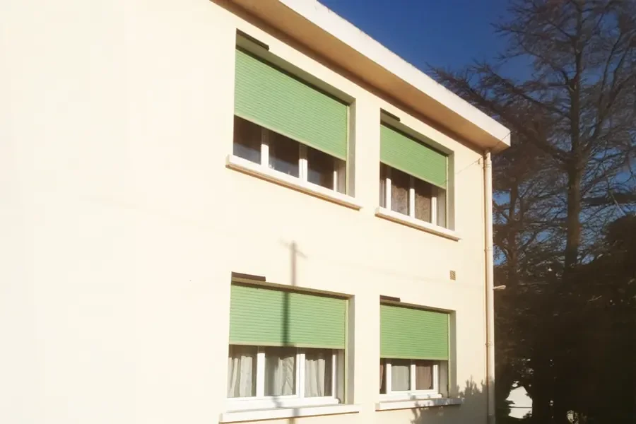 Terrasse extérieure d'habitation avec mobilier de jardin blanc, table ronde et chaises en plastique