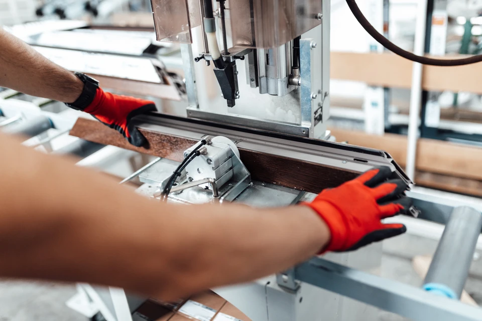 Le travailleur manuel travaille dans une usine de menuiserie, il monte des fenêtres et des portes en PVC