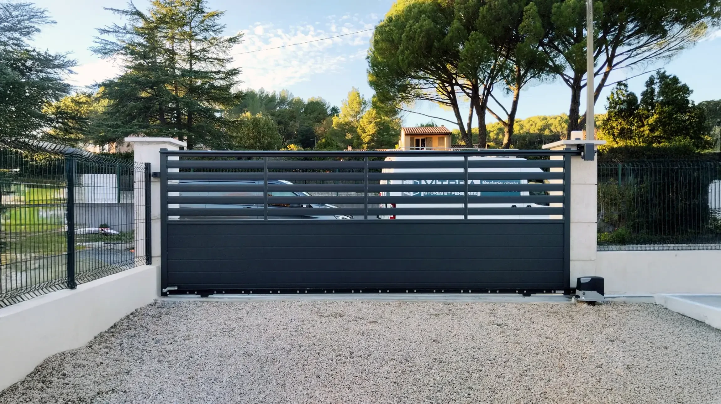 Terrasse couverte moderne avec grandes baies vitr&eacute;es coulissantes donnant sur jardin paysag&eacute;