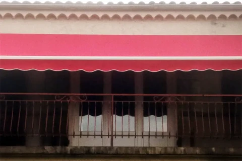 Façade commerciale traditionnelle avec auvent rouge et balustrade métallique, architecture coloniale typique d'une zone d'activité artisanale ou commerciale de quartier